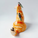 Glossy ceramic sculpture of an orange tiger with a carved pattern of poppy flowers on its body, with various stripes. Sitting on its back and head are small black magpie birds.