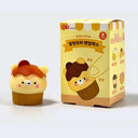 Small squishy rubber figurine of a bear as a cupcake - within a brown cupcake liner and with a dollop of brown sauce atop of it. It sits next to its product packaging.