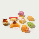 8 small food themed squishy rubber figures, all with tiny cute faces on them. Options are: cupcake, hotdog, croissant, swiss roll, dumpling, pastry horn and heart shaped cookie.