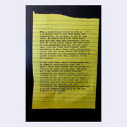 Featuring a yellow lined sheet of paper with typewritten story atop of it, page excerpt.