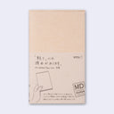 Light tan blank cover for a notebook, within packaging with Japanese script and an illustration of a hand holding a paper cover.