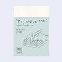 MD Notebook packaging with a hand holding a pen on a light blue background