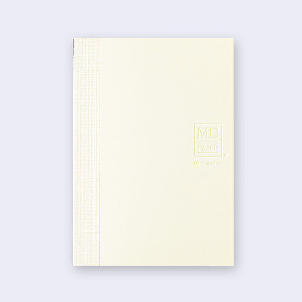 Cream-colored notebook with grid patterned binding and "MD paper" branding on the side.