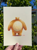Illustration of a large, round bear with a disproportionately small head, held in someone's hand in front of greenery.