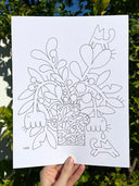 Line art illustration of a vase of flowers, with cartoon cats around them and fish on the vase. Held in someone's hand against greenery.