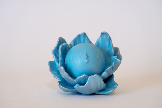 Blue flower-shaped object with a spherical center that has a calm, closed eye face.