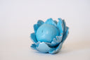 Blue flower-shaped object with a spherical center that has a calm, closed eye face.
