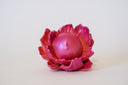 Pink flower-shaped object with a spherical center that has a calm, closed eye face.