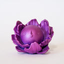 Purple flower-shaped object with a spherical center that has a calm, closed eye face.