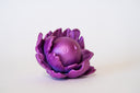 Purple flower-shaped object with a spherical center that has a calm, closed eye face.