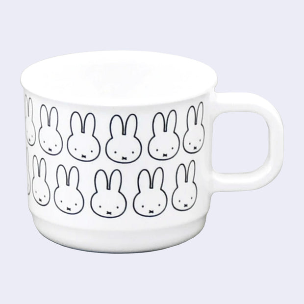 Small white handle mug with a repeating design of Miffy's face, with her small eyes and x shaped mouth. 