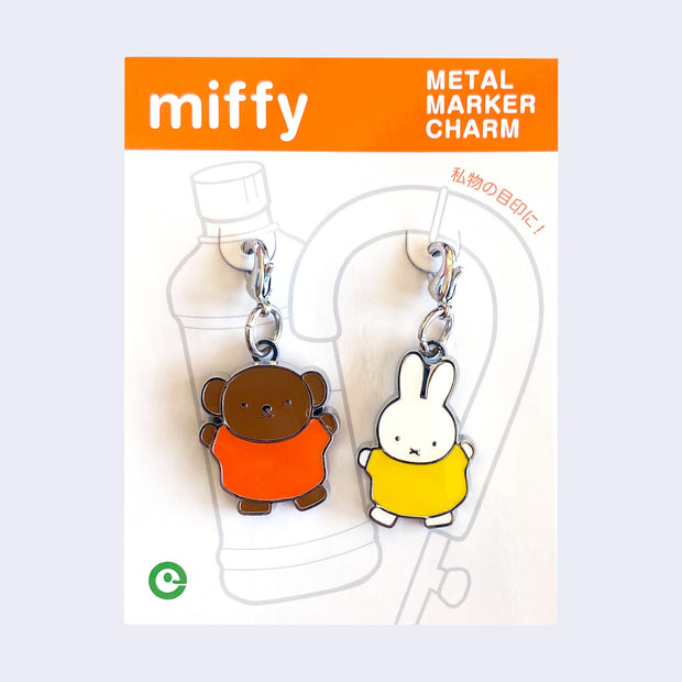 2 die cut metal charms, one of Miffy in a yellow dress and one of Miffy's friend Boris the bear, in her orange dress. Each are attached to their own clasp on a white backing card.