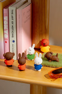 Small figurines of animals on a wooden surface with books in the background