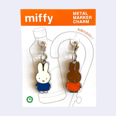 2 die cut metal charms, one of Miffy in a blue dress and one of Miffy's friend Melanie, in her orange dress. Each are attached to their own clasp on a white backing card.