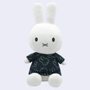 Plush Miffy doll, sitting with a dark navy shirt dress that is patterned with small Miffy heads on it.