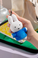 White plush Miffy keychain with a blue sweater held by a hand.