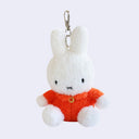 Fluffy white bunny keychain, wearing an orange dress.