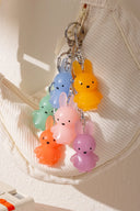 Colorful bunny-shaped keychain hanging on a textured beige surface