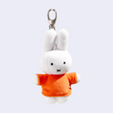 Plush keychain of a white rabbit character wearing an orange sweater on a light gray background