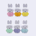 Set of six small Miffy rabbit figurines in different colored outfits on a light gray background