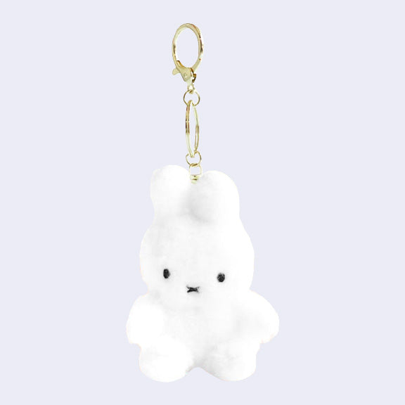 White fluffy bunny-shaped keychain with a gold clip on a light purple background