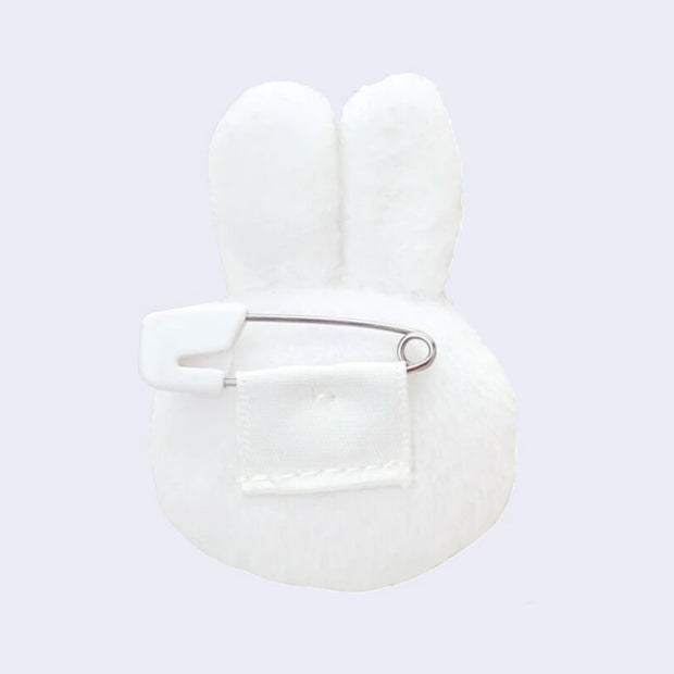 White bunny-shaped plush with ears, seen from the back with a safety pin attachment.