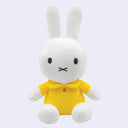 Plush Miffy doll, sitting with a yellow shirt dress and a small embroidered yellow button.