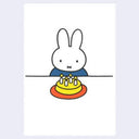 Postcard with an illustration of Miffy, sitting at a table in front of a birthday cake with candles. 