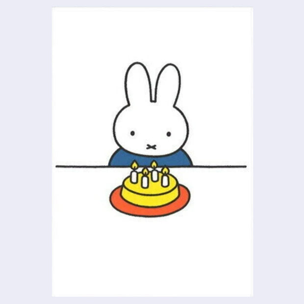 Postcard with an illustration of Miffy, sitting at a table in front of a birthday cake with candles. 
