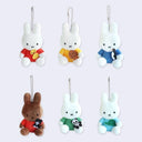 Plush keychains of Miffy, 6 different varieties all sitting and holding a different 2D animal. Each Miffy wears a different colored shirt and the animals being held are: duck, dog, penguin, cat, panda and turtle.