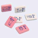 6 pastel-colored rectangular erasers with blue cartoon illustrations and the brand name 'MILAN 460' printed on them, arranged on a light gray background.