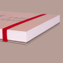 Side view of a sketchbook of watercolor paper with a beige cover and orange elastic band wrapping around it. Text on the front reads "Milan - 1420 The Master Gum"