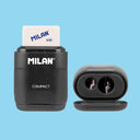 Black Milan compact sharpener with a white eraser on a blue background