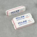 3 white erasers with slightly angled edges and a pink line going around their exterior. Text on each says "milan 620 nata"