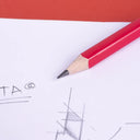 Close up of a graphite pencil with a sharp tip and a red wooden body on paper.