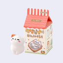 Small and cute cat figurine standing in front of its product packaging, which is shaped like a house with Korean text and images of cats