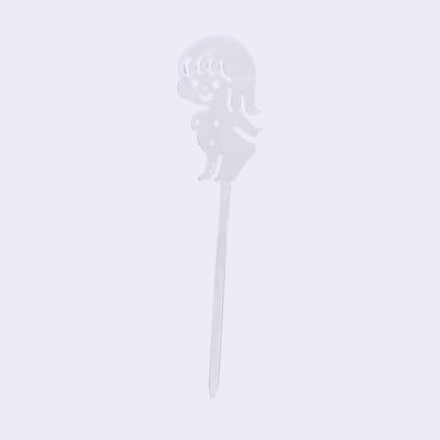 Clear acrylic die cut drink stirrer of a nude cartoon girl, standing with her arms extended behind her back.