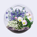 Clear glass sphere with a variety of colorful flowers on a light gray background