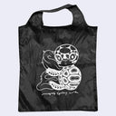 Black tote bag with white turtle design on a light gray background