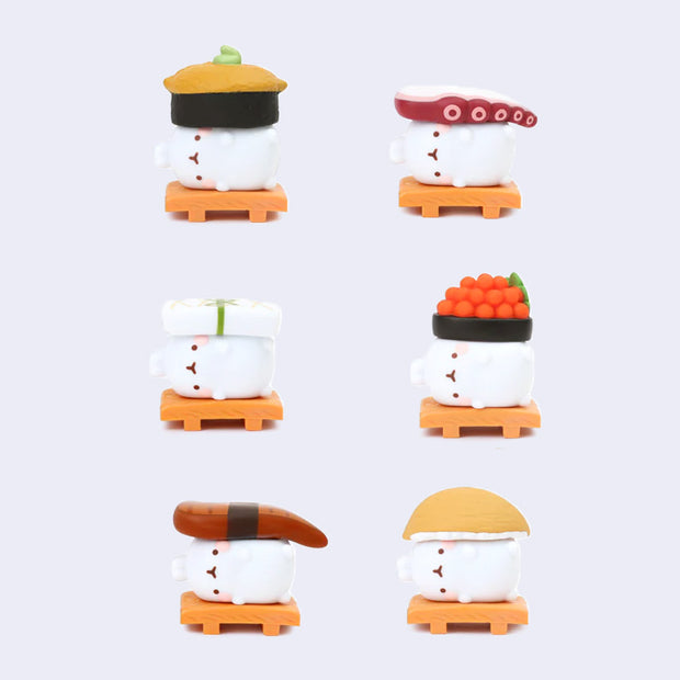 Set of six small figurines of bunnies laying on a bamboo platter, topped with sushi.