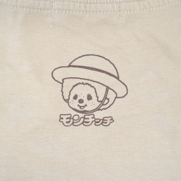 Small logo on the back of a t-shirt of Monchhichi wearing a straw hat and smiling.