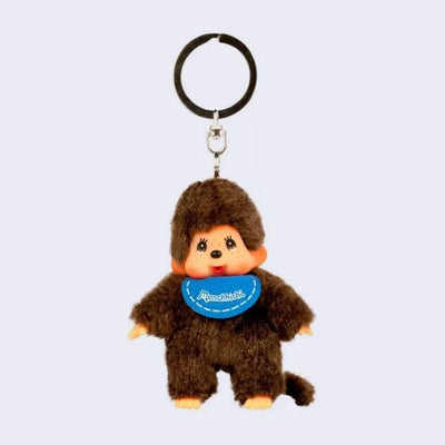 Small plush keychain of a Monchhichi doll,  fluffy monkey plush with a cute face. It wears a blue bib.
