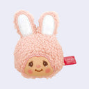 Plush face of Chimutan, a cute pink rabbit with cartoon eyes and rosy cheeks. It has a tag coming out of the side of it.