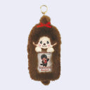 Plush keychain of a Monchhichi character with a clear sleeve in the center, as a place to put a photo. The plush photo holder is attached to a gold hardware keychain.