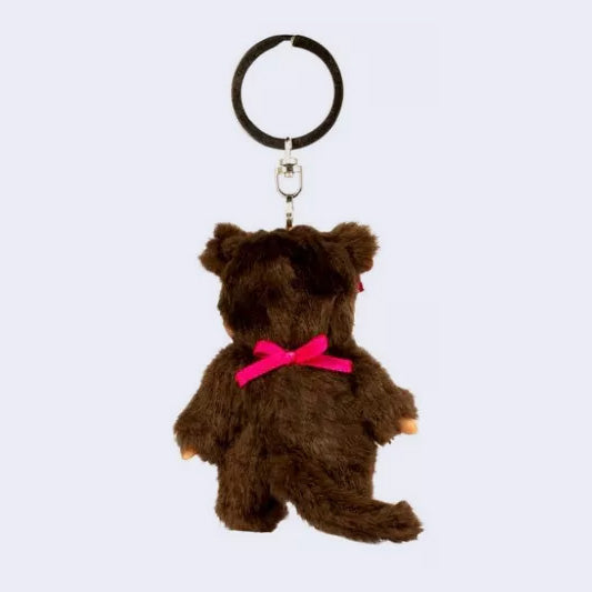 Small plush keychain of a Monchhichi doll, a fluffy monkey plush with a cute face and its hair in pigtails tied by pink bows. It wears a pink bib.