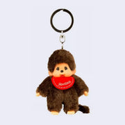 Small plush keychain of a Monchhichi doll, a fluffy monkey plush with a cute face. It wears a red bib.