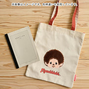 Tote bag with cartoon Monchhichi character and notebook on a wooden surface