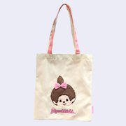 Tote bag with a cartoon Monchhichi girl with a pink bow and 'Monchhichi' branding on a light background