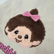 Tote bag with a cartoon Monchhichi girl with a pink bow and 'Monchhichi' branding, close up to show detail.
