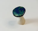 Back side of mushroom sculpture, with a shiny blue and green flat mushroom top.